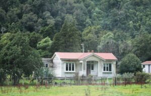A white weatherboard house with a red roof on the West Coast
