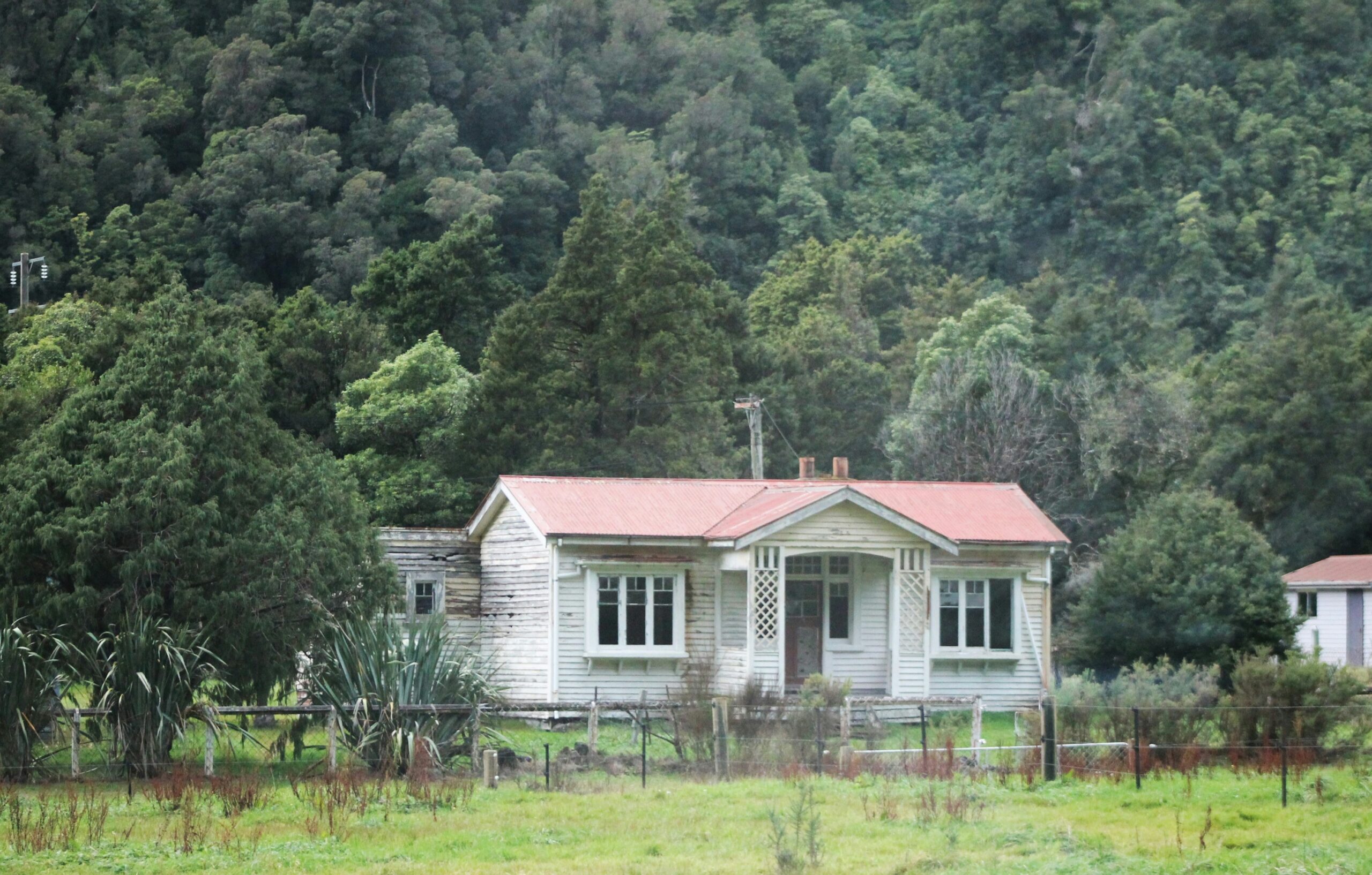 A white weatherboard house with a red roof on the West Coast