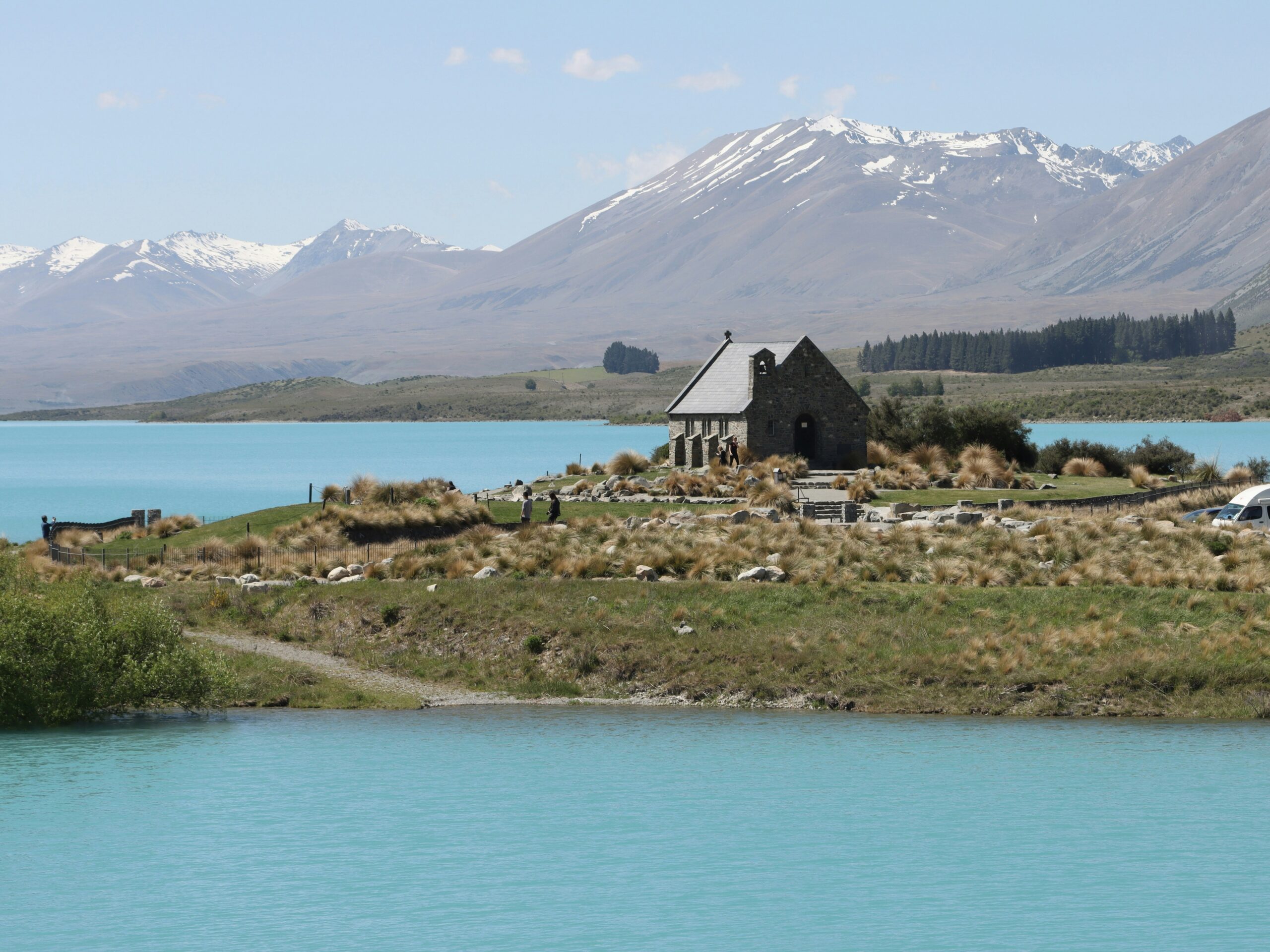 A small stone building beside Lake Tekapo with mountains beyond
